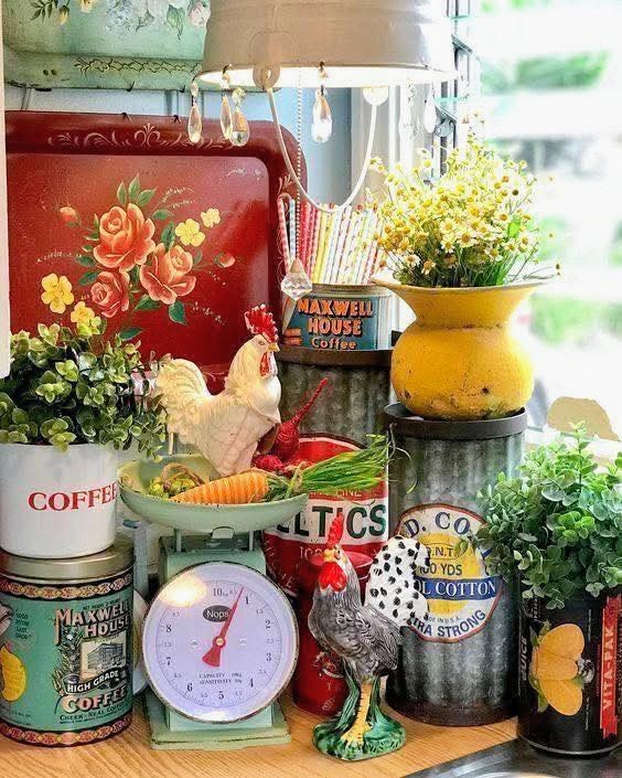 Vintage kitchen decor with floral tins, rooster figurines, old scales, and flowers on a windowsill