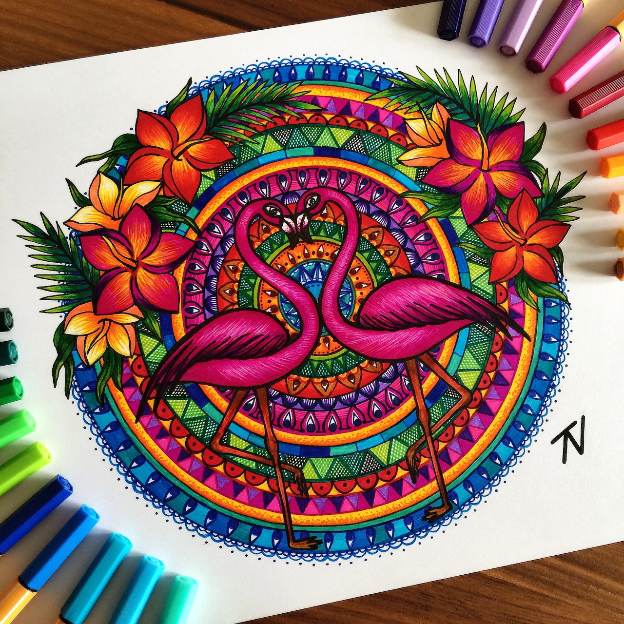 Colorful mandala drawing with flamingos, flowers, and geometric patterns on paper with colored pencils