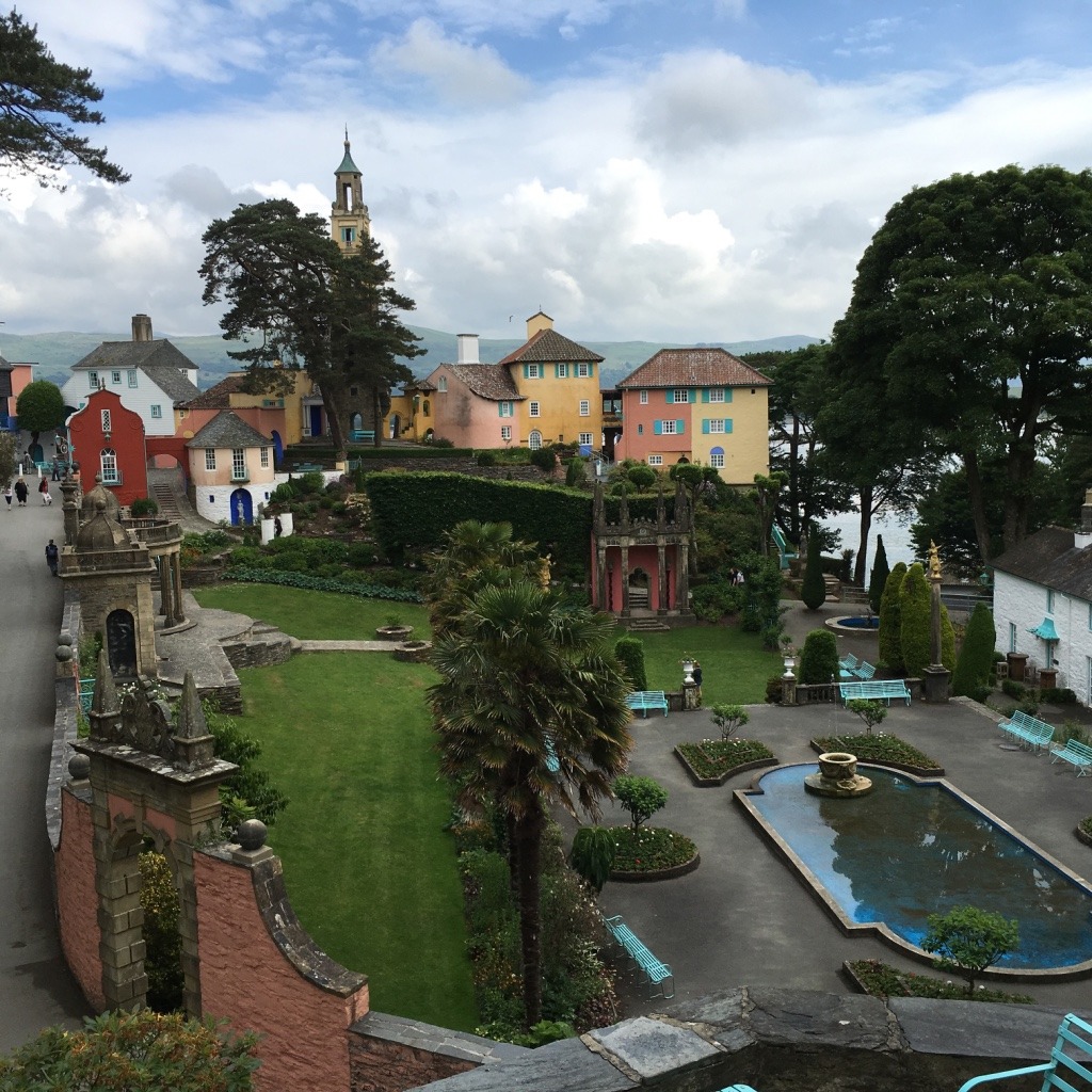 Elevated view of Portmeirion village with pastel buildings, gardens, and a fountain courtyard