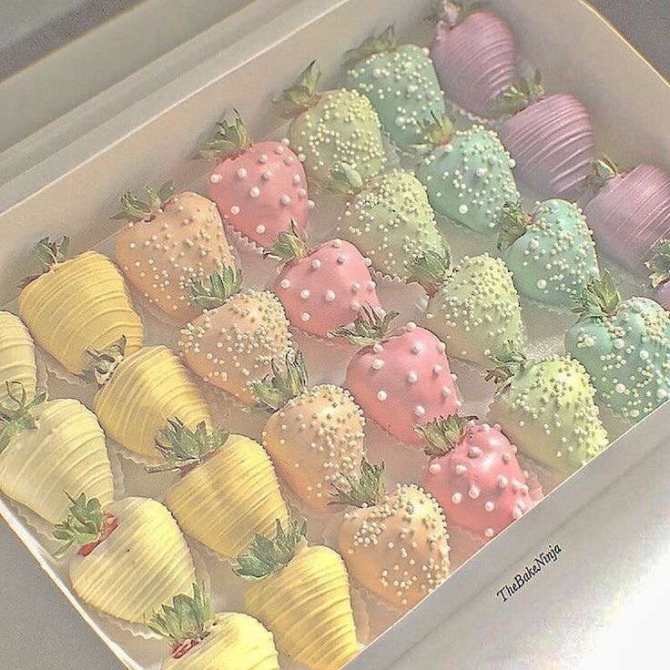 Pastel colored chocolate covered strawberries with decorative toppings in a white box