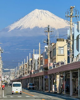 Urban street with utility poles and Mount Fuji covered in snow in the background