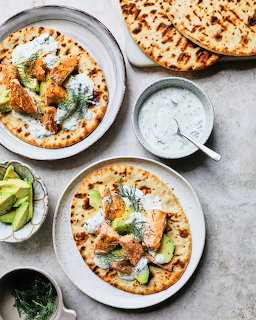 Two bowls of Indian curry with naan bread, cream sauce, and cilantro garnish on marble countertop