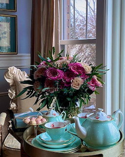 Turquoise tea set and purple rose bouquet on tray by window