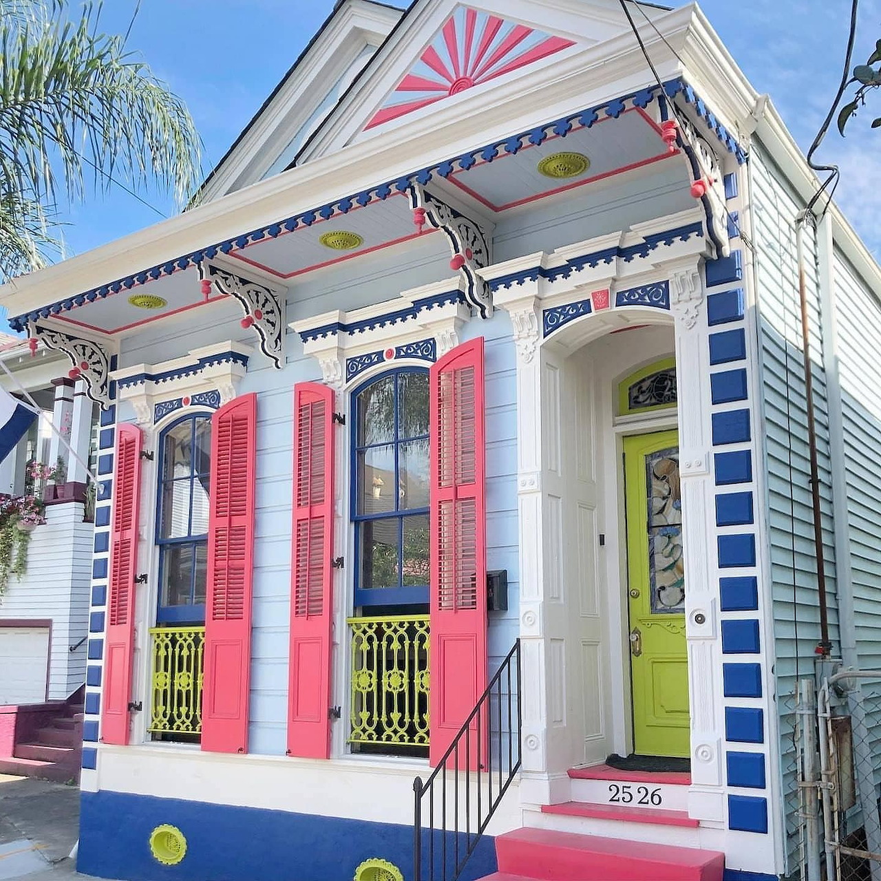 Colorful Victorian house with pink shutters, lime green door, and blue decorative trim