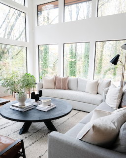 Bright modern living room with white sofa, round black coffee table, and floor-to-ceiling windows