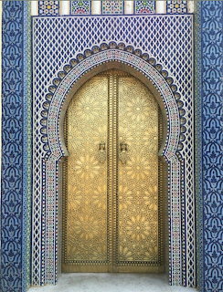 Ornate golden Moroccan door with blue geometric tile surround and horseshoe arch