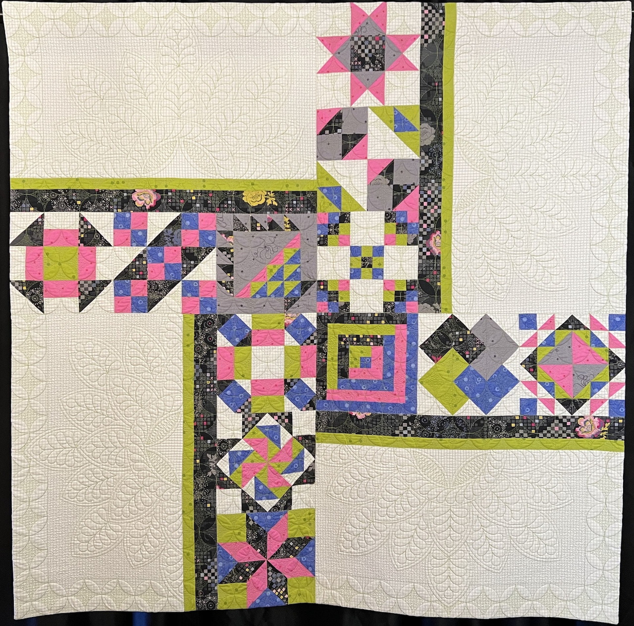 Modern geometric quilt with colorful patchwork blocks arranged in asymmetric border pattern on cream fabric