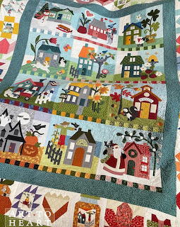 Handmade patchwork quilt with farm-themed squares including barns, tractors, animals, and rural buildings