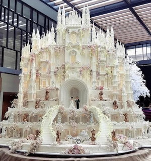 Huge white wedding cake shaped like a gothic cathedral displayed indoors