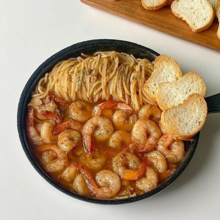 Pan of pasta with shrimp in tomato sauce served with toasted bread