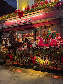 Illuminated Clos Maggiore restaurant decorated with Christmas lights, red sleigh, and festive garland at night