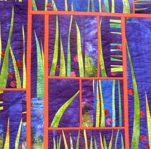Abstract quilt with purple and blue panels, green leaf-like strips, and orange geometric borders