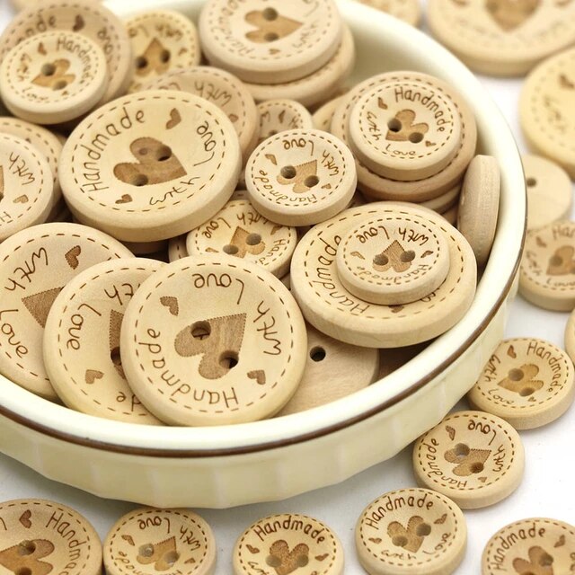 Pile of round wooden buttons with engraved hearts and text in a white bowl