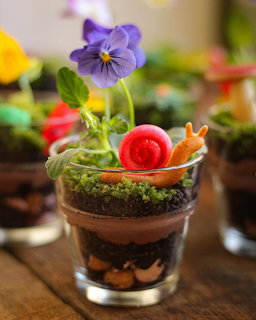 Chocolate layered dessert in glass with purple pansy flower and red snail decoration