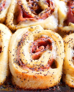 Close-up of spiral ham and cheese rollups with poppy seeds and glaze on dark surface