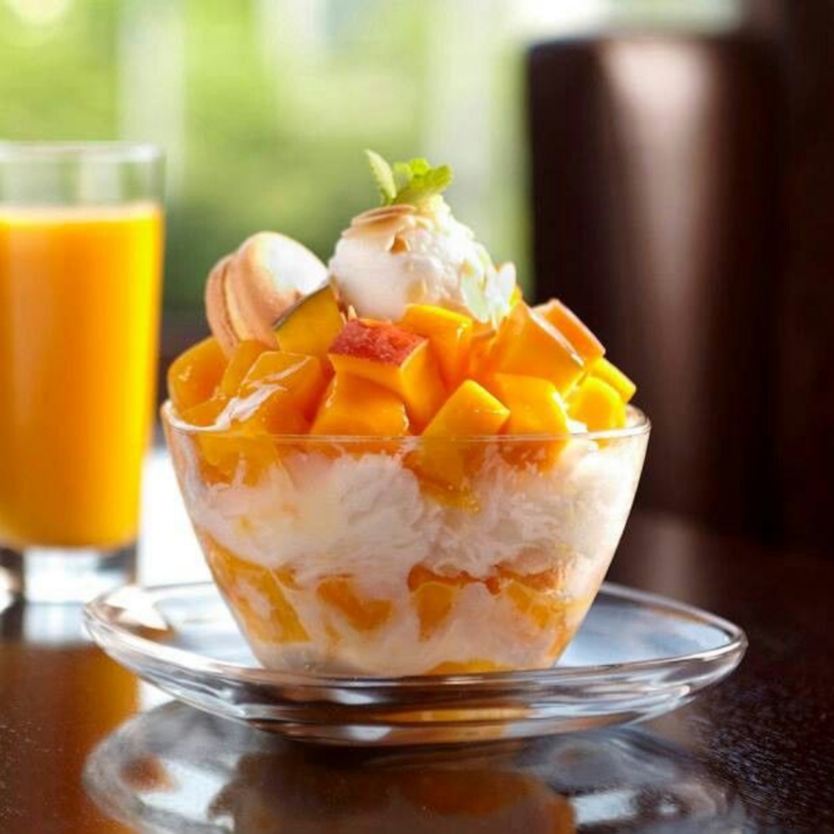 Mango shaved ice dessert in a glass bowl topped with mango cubes and whipped cream