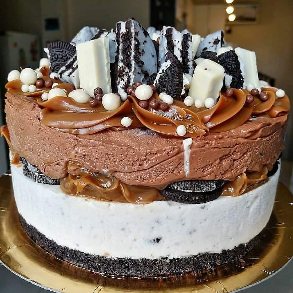 Round layered cake with chocolate frosting, Oreos, caramel drizzle, and marshmallows on top