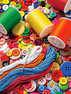 Colorful thread spools and assorted buttons with embroidery floss on button background