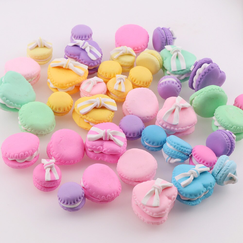 Colorful pastel macaron miniatures in various shapes with decorative bows on a light background