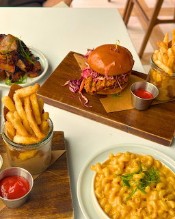 Overhead shot of burger, fries, mac and cheese, and sides on restaurant table