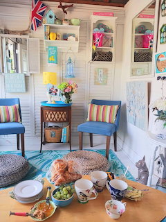 Cozy white room with a tea table, colorful chairs, and an orange cat resting on a floor cushion