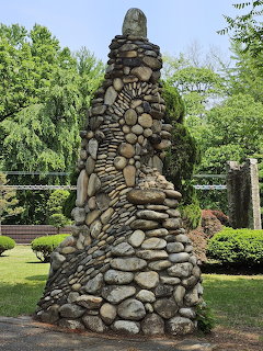 Tall stacked river rock sculpture in a green garden at Nami Island, South Korea