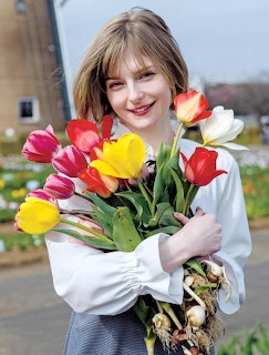 Smiling young woman holding a bouquet of red, yellow, pink, and white tulips outdoors