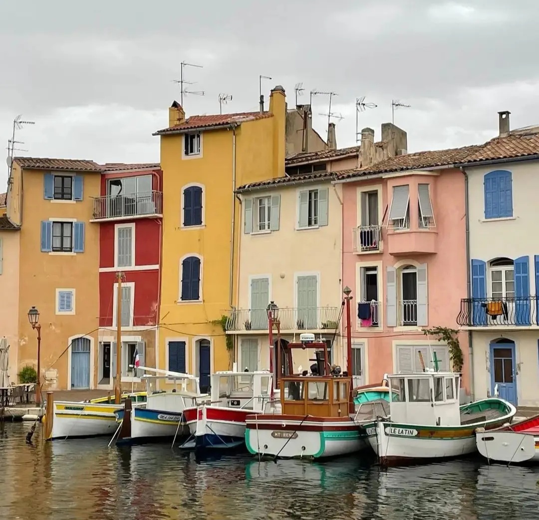 Pastel waterfront houses and small boats along a calm canal