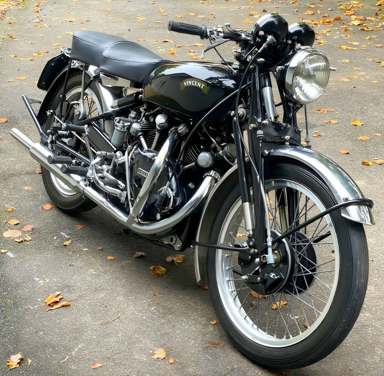 Vintage 1949 Vincent Black Shadow motorcycle with dark green tank and chrome engine parked on leaf-covered ground
