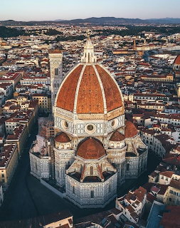 Aerial view of Florence Cathedral with red dome and bell tower over city rooftops