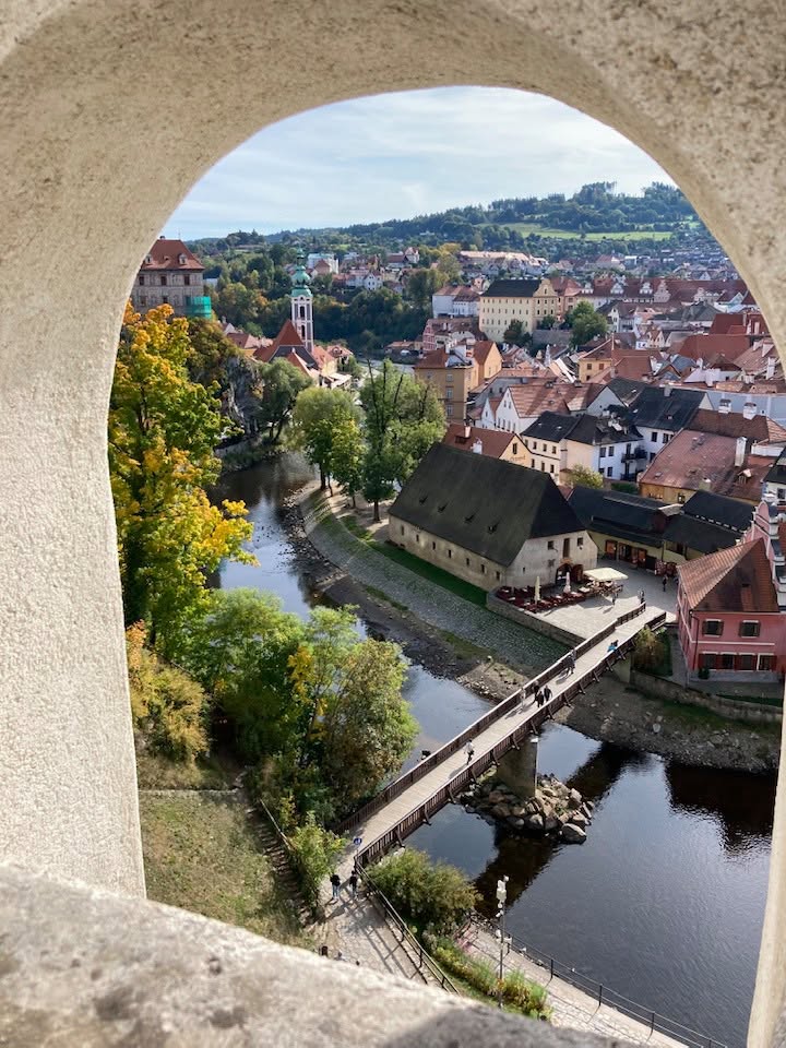 View of Cesky Krumlov town with river and bridge through stone arch window