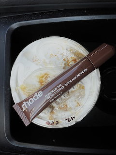Brown squeeze tube placed across a cup of whipped cream or frothy dessert in a black tray