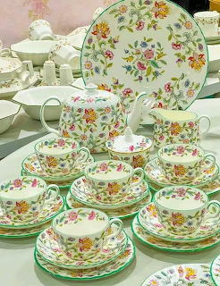 Vintage floral porcelain tea set with cups, saucers, teapot, and plates decorated with colorful flowers and green trim.