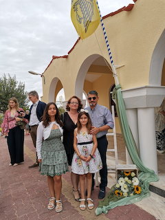 Group of people posing outside a yellow church with arches and flower decorations
