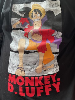 Black t-shirt with Monkey D. Luffy character graphic and red text on fabric background