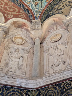 Ornate baptistery interior with carved stone reliefs, arches, and colorful mosaic ceiling details