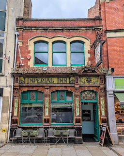 Ornate Victorian pub facade with green tilework and arched windows in Gloucester, England