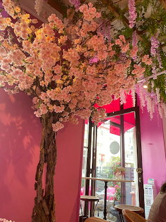 Decorative cherry blossom tree with pink flowers inside a pink-themed cafe interior