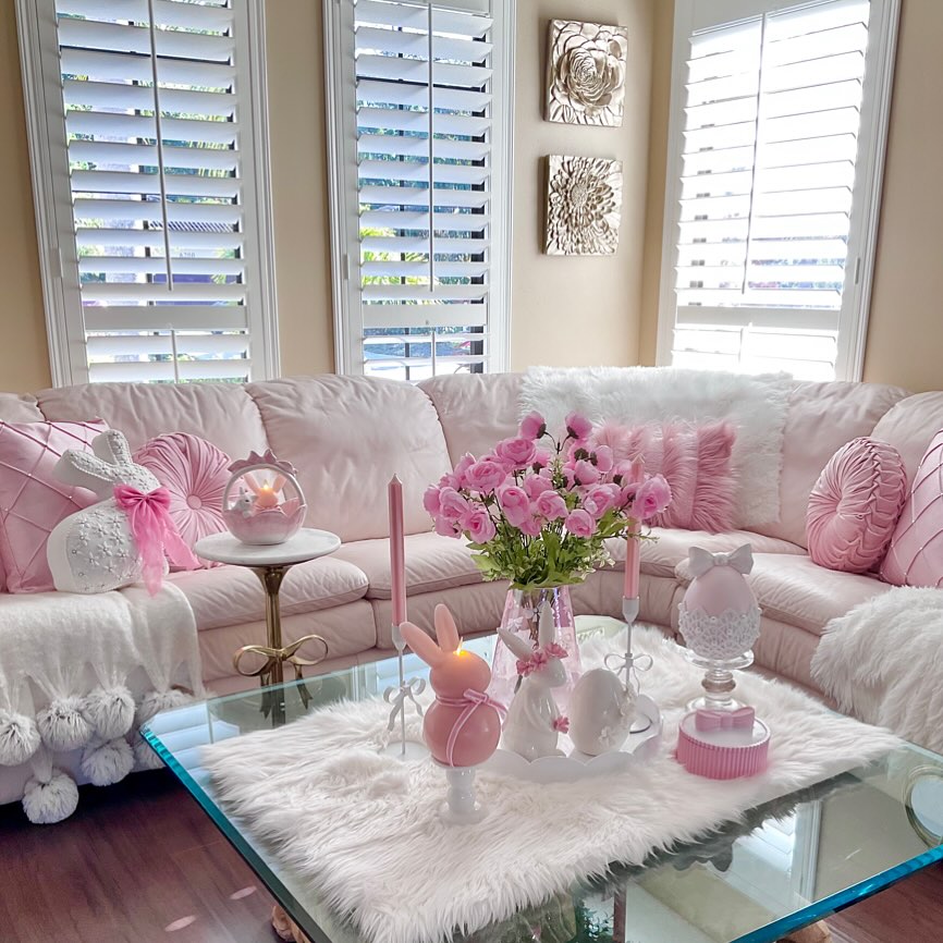 Bright living room with white furniture, pink tulips on coffee table, and soft pink decorative accents