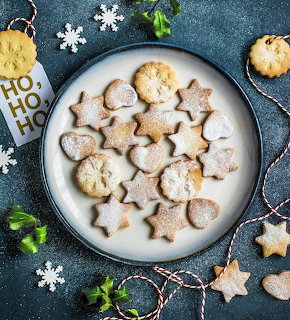 Star-shaped Christmas cookies with powdered sugar on a white plate with holiday decorations