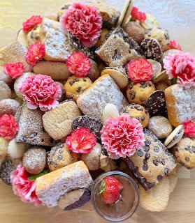Pile of assorted cookies and pastries decorated with pink carnation flowers