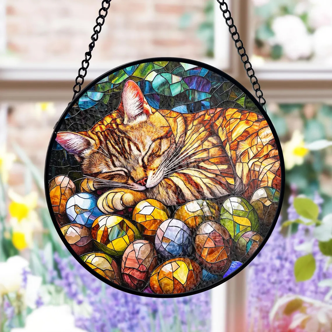 Circular suncatcher with orange tabby cat sleeping among colorful Easter eggs in stained glass style