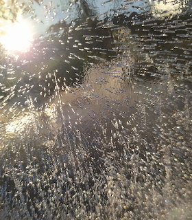 Close-up of ice crystals on a frozen surface with sunlight gleaming through