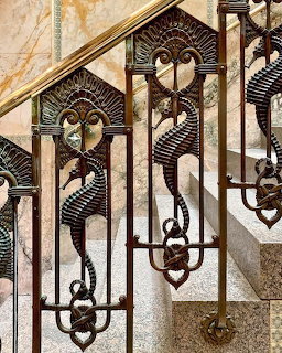 Decorative Art Nouveau wrought iron staircase railing with geometric and floral designs on marble stairs