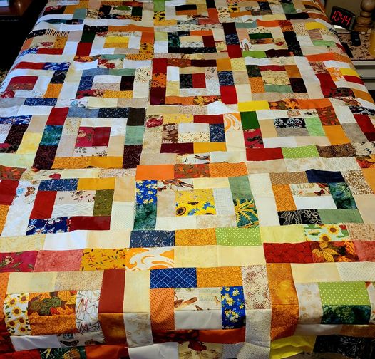 Colorful patchwork quilt with fabric squares in concentric patterns on dark surface