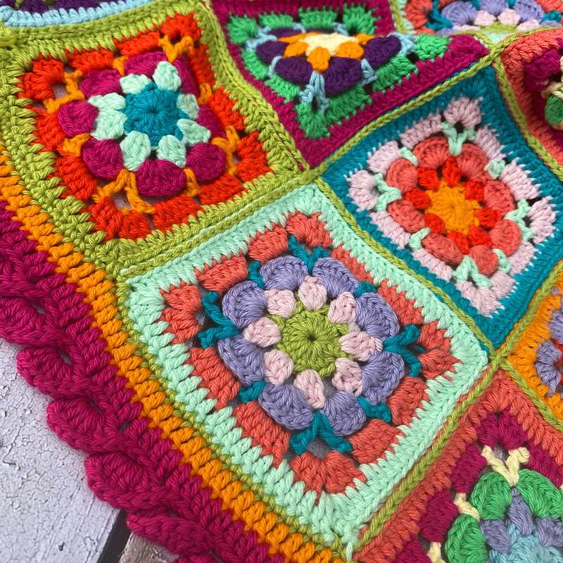 Colorful crochet granny square blanket with floral pattern in rainbow colors