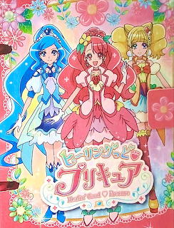 Three Healin Good Precure anime characters in colorful magical girl costumes with flowers