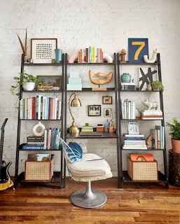 Bookshelf with books, plants, baskets, decor, and a white chair in a cozy room