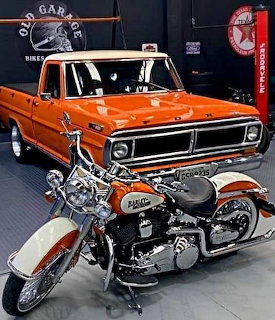 Orange vintage Ford pickup truck and white classic motorcycle in a garage with retro signs