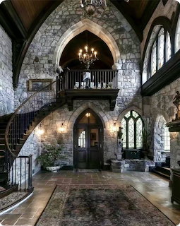 Victorian-style stone interior with arched windows, staircase, balcony, and chandeliers